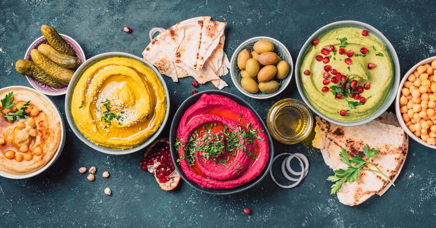Red, Yellow and Guacamole hummus bowls on a dark table